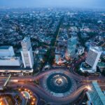 Home Stunning aerial view of Jakarta's bustling cityscape with illuminated roundabout at twilight.